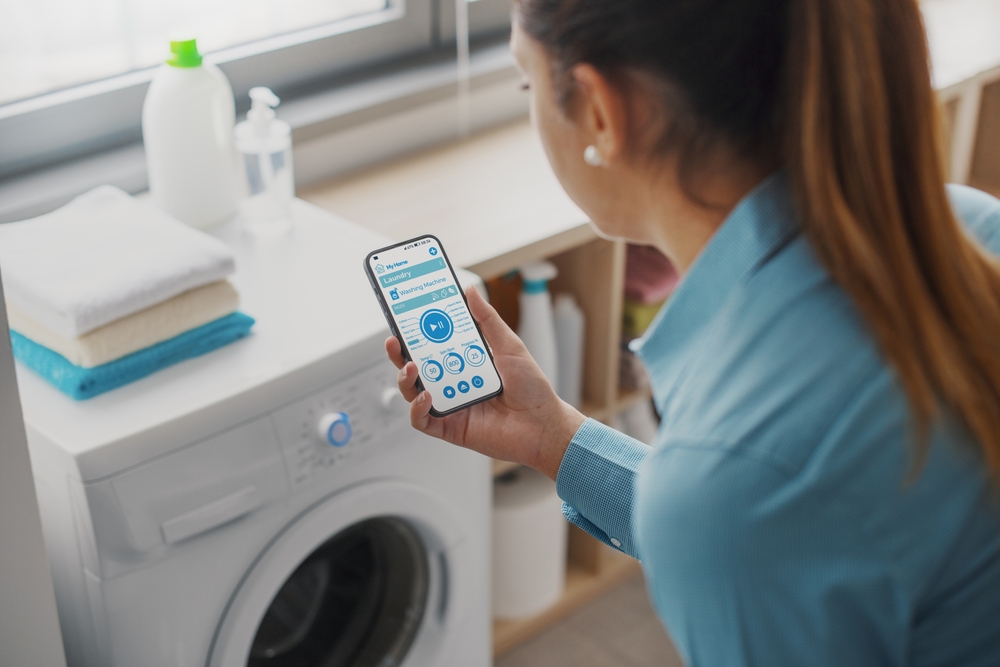 Woman using smartphone to control washing machine